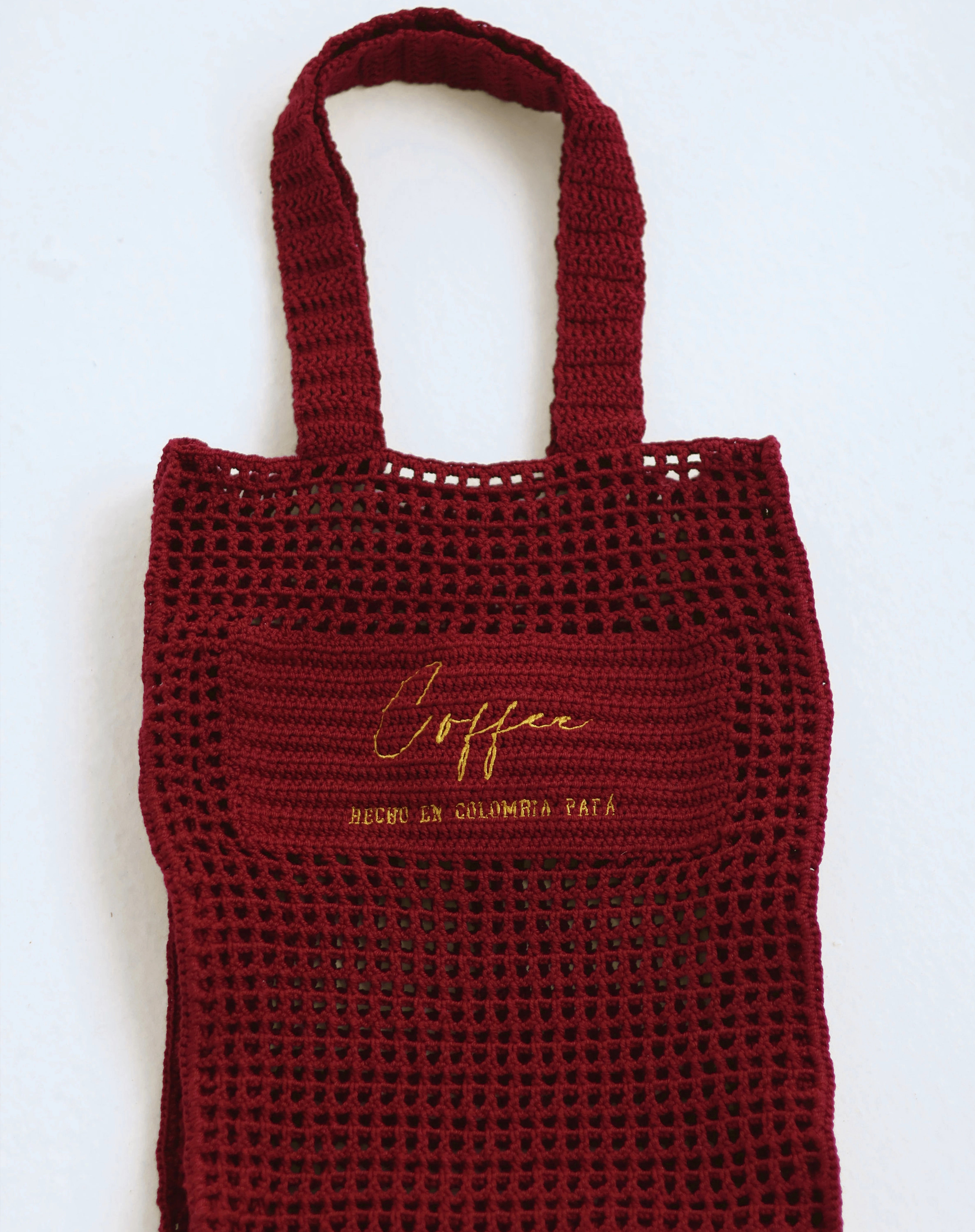 Bolso tipo tote en algodón orgánico tejido a mano, color cereza con la etiqueta "Café - Hecho en Colombia PAPA", diseño minimalista y sostenible diseñado por Coffee Clothing.