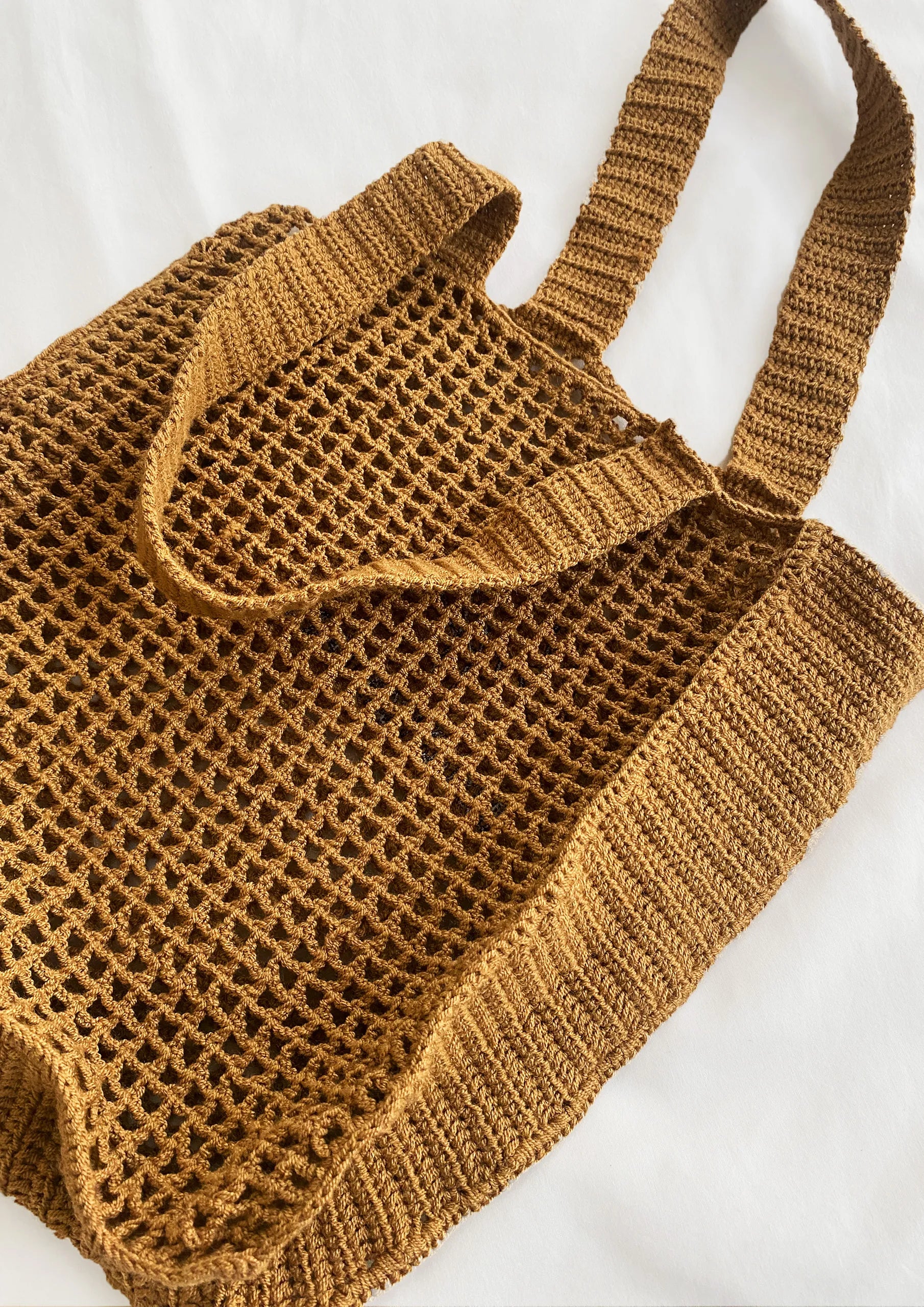 Primer plano de la bolsa tote de algodón orgánico tejida a mano en color camel. Diseño minimalista y sostenible de Coffee Clothing.