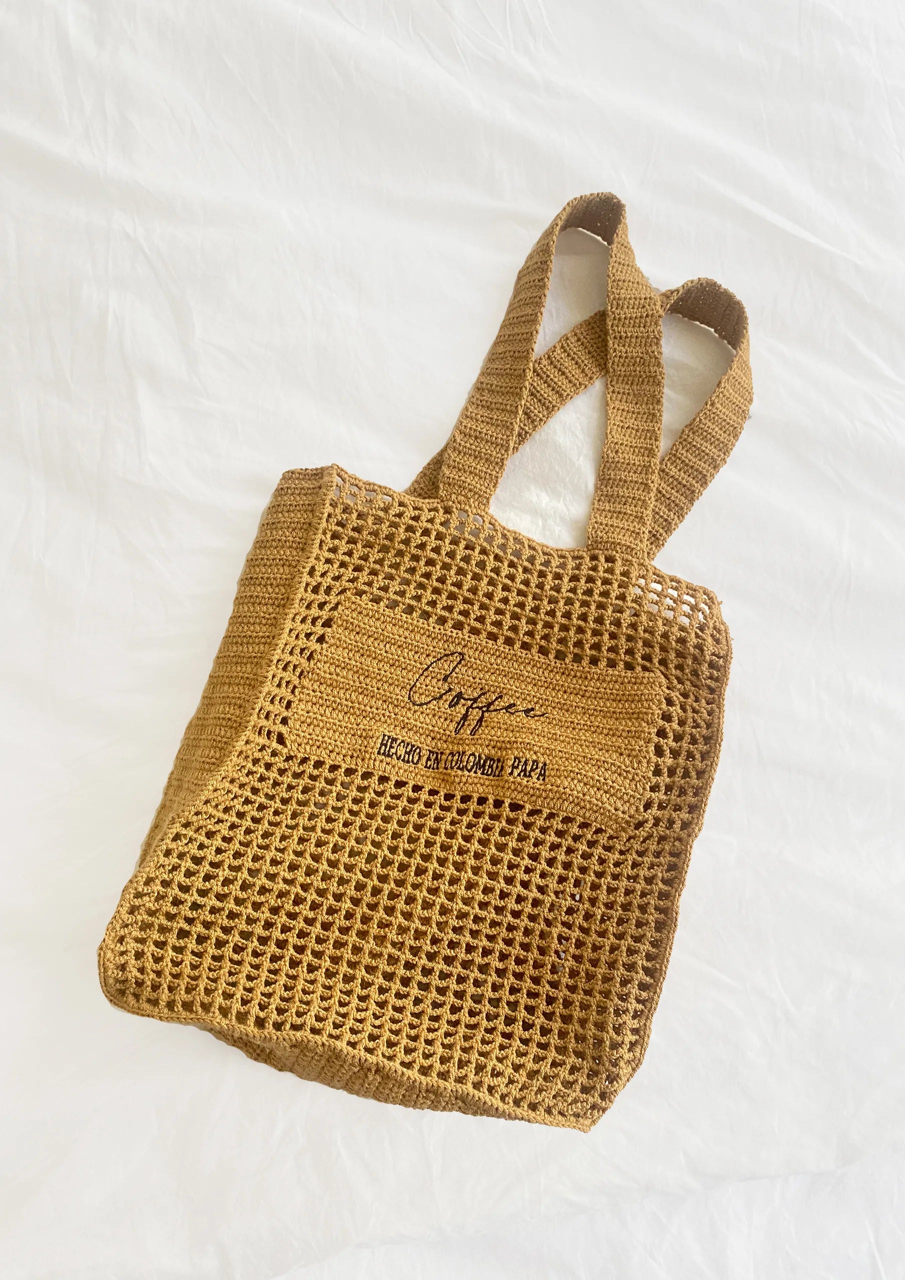 Bolso tipo tote en algodón orgánico tejido a mano, color camel con la etiqueta "Café - Hecho en Colombia PAPA", diseño minimalista y sostenible diseñado por Coffee Clothing.